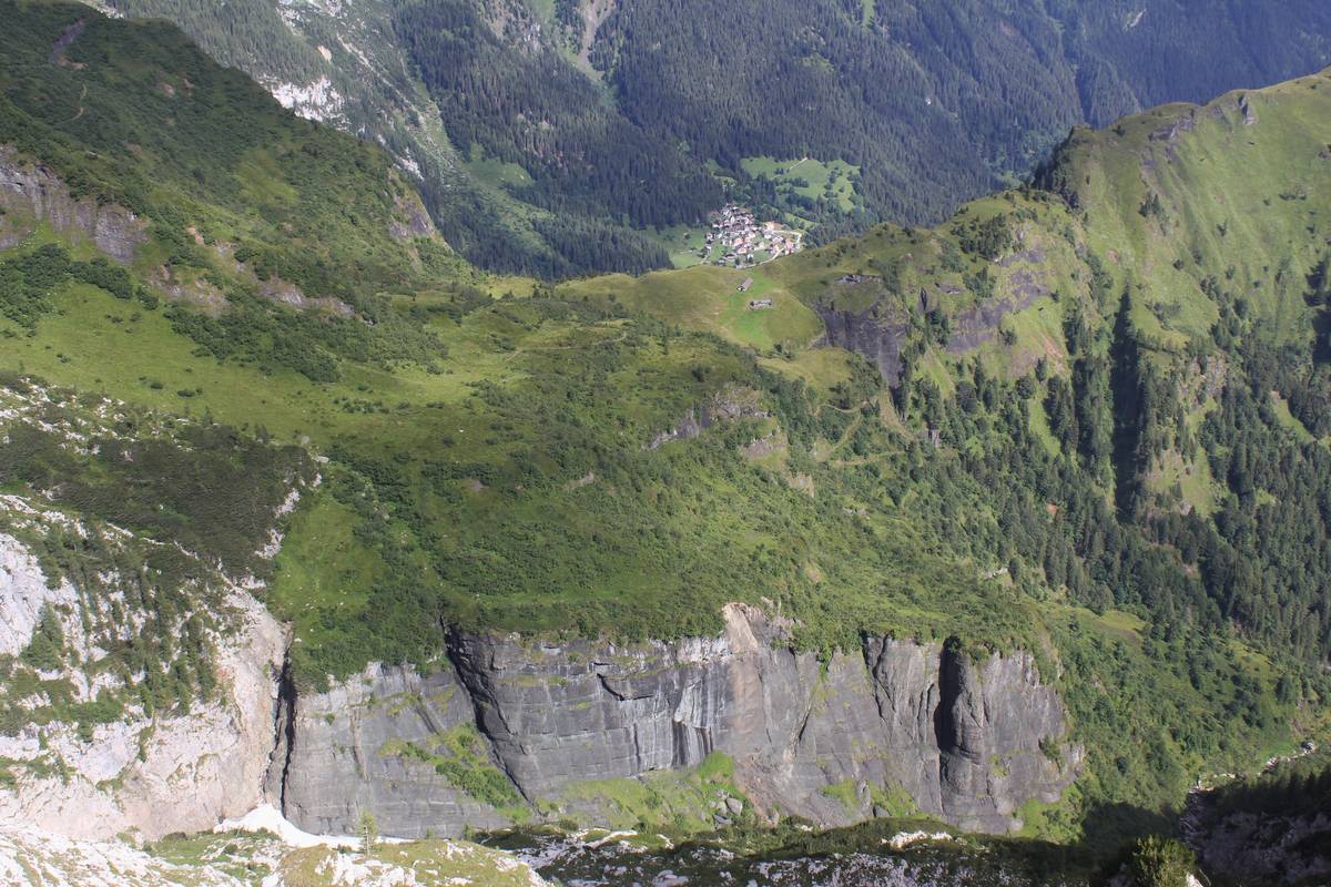 Forcella Cesurette e Casera Campigat, oltre la cresta spunta il villaggio di Garès; si può notare la strada militare che sale con diversi tornanti verso la casera; dalla casera il percorso continua seguendo la cresta verso destra. Sulla sinistra in primo piano è visibile il contatto (tettonico per faglia trascorrente destra) fra le rocce chiare della scarpata di scogliera e le lave a pillow rimaneggiate di colore scuro (foto Lucio D’Alberto)